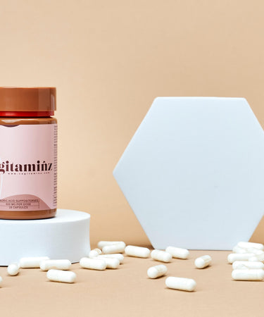 Two bottles of the best vaginal suppositories, one displayed on a round white block and the other tipped over spilling the suppositories.
