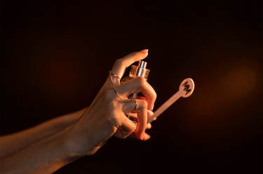A person spritzing perfume onto a scent tester strip.